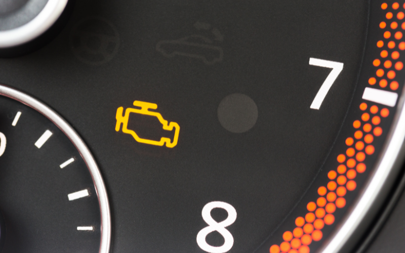 Close-up of a car driver's display showing engine warning light